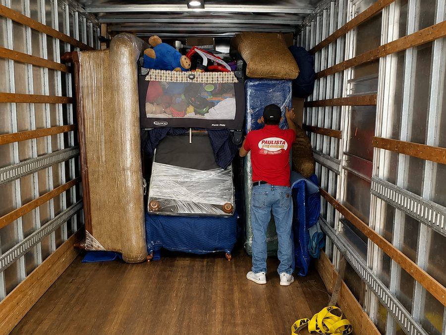 Paulista Moving crew member loading wrapped furniture and household items into the moving truck